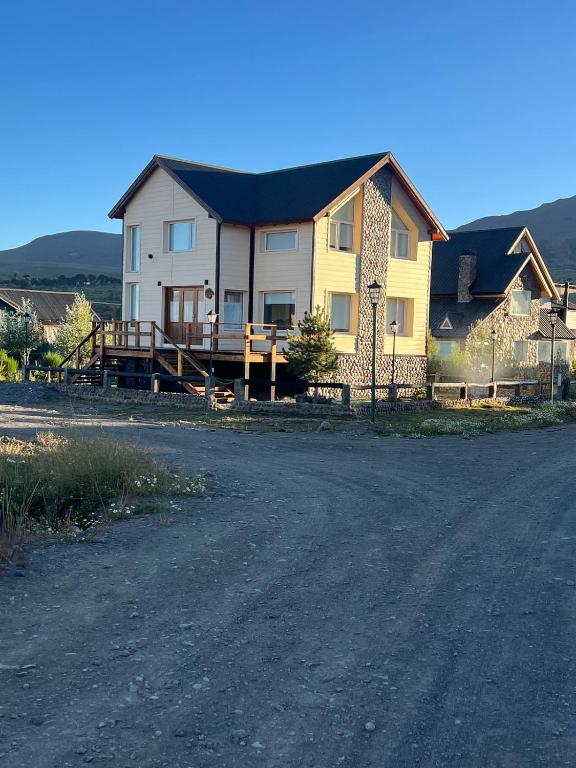 a large yellow house with a fence on the side of a road at Cabaña Macar in Caviahue