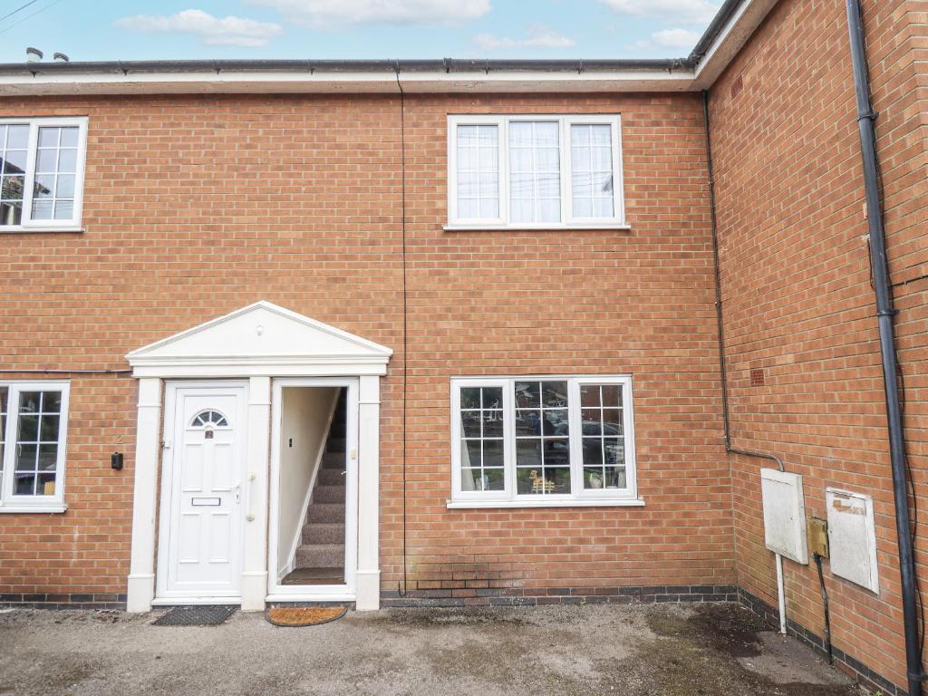 ein Backsteingebäude mit einer weißen Tür und einer Treppe in der Unterkunft 5 Links Court in Skegness