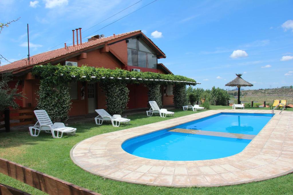 a villa with a swimming pool in front of a house at Posada Cacheuta in Las Compuertas