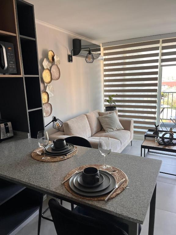 eine Küche und ein Wohnzimmer mit einem Tisch mit Weingläsern in der Unterkunft Estadio Nacional Ñuñoa in Santiago