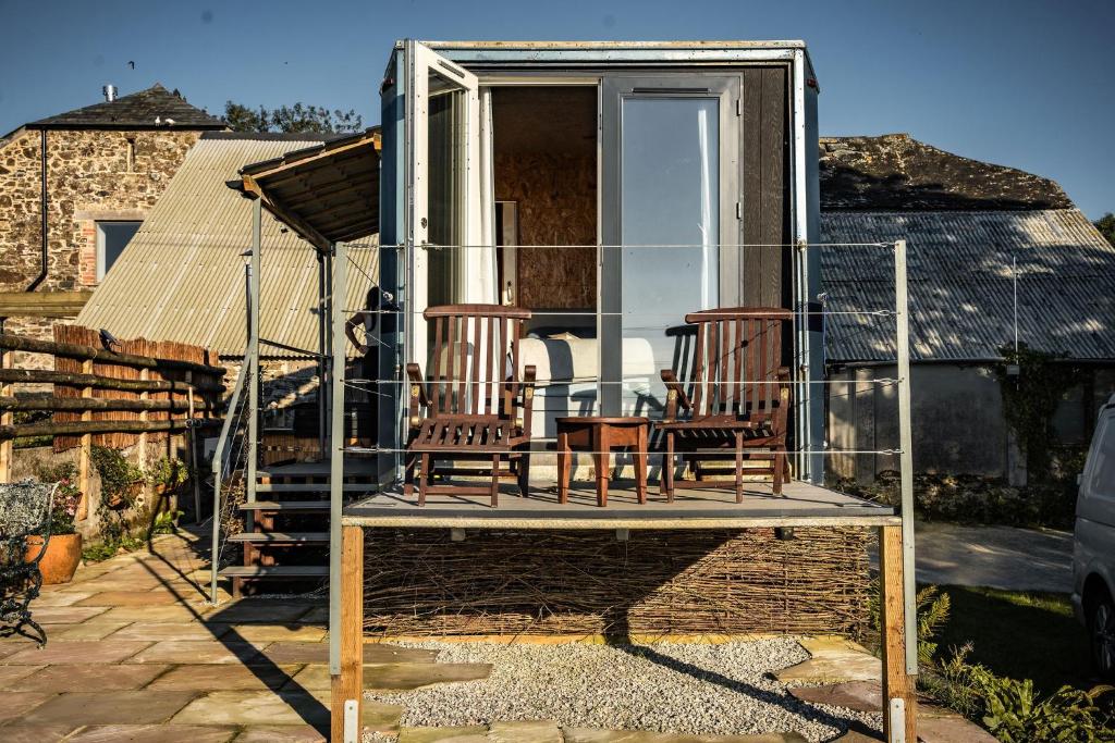 a house with three chairs sitting on a porch at Unique Glamping Experience - The Horse Box in Bradstone