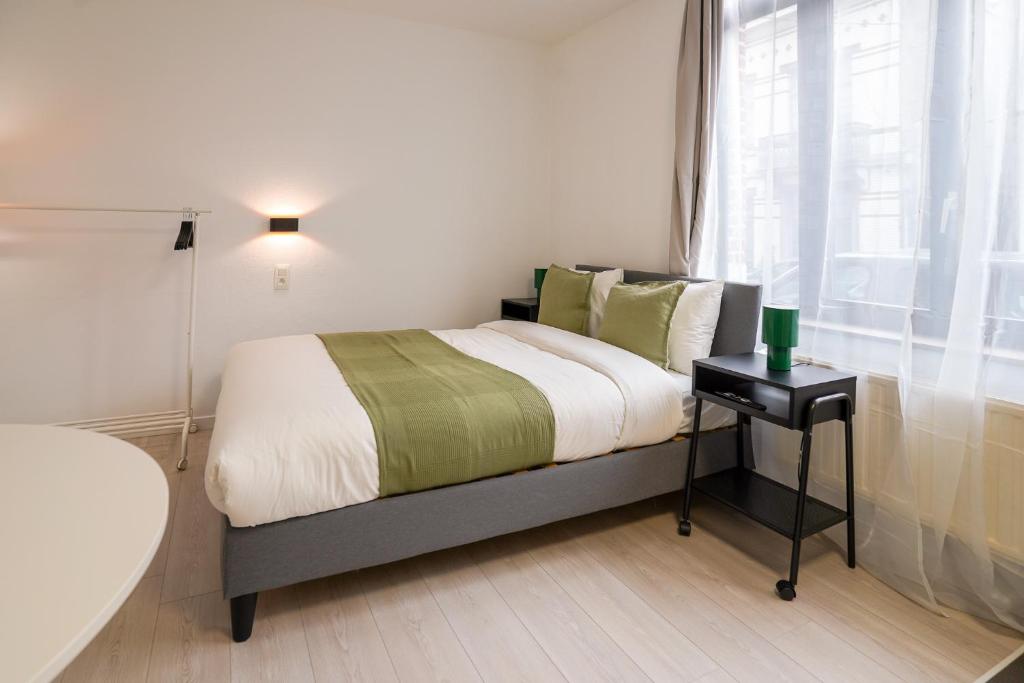 een slaapkamer met een bed met een tafel en een raam bij Cinquantenaire 1 in Brussel