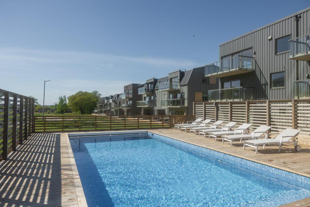 a swimming pool with lounge chairs next to a building at Luxury Living at Ekerum Öland Heated Pool, Golf & Sea! in Borgholm