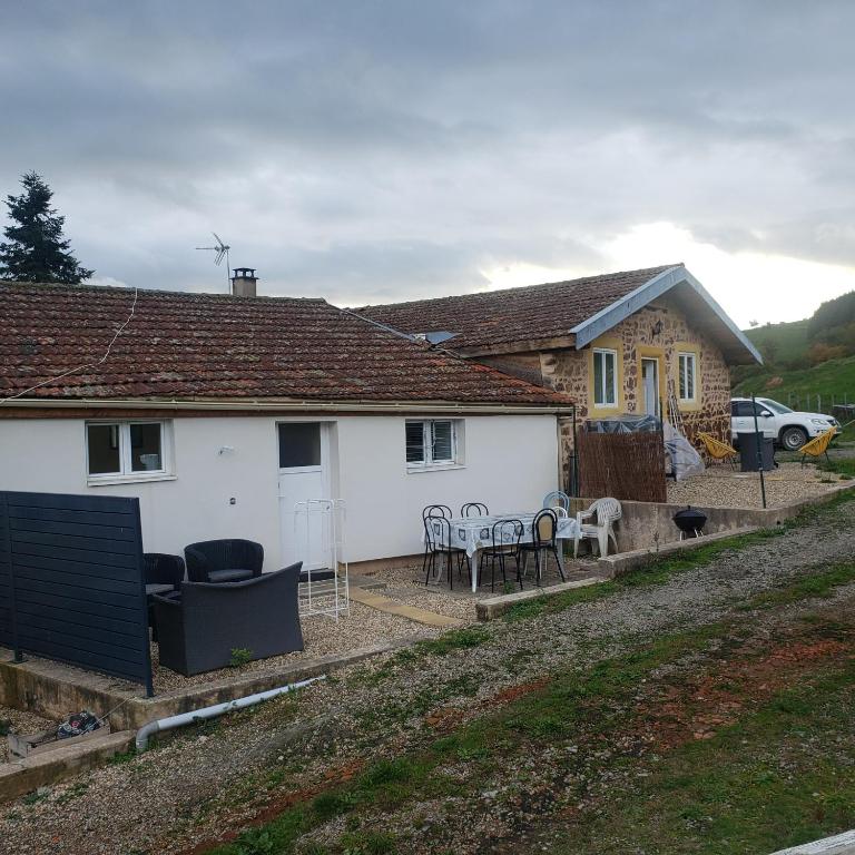 a white house with chairs and tables in front of it at Charmante maison de campagne in Pont-Trambouze