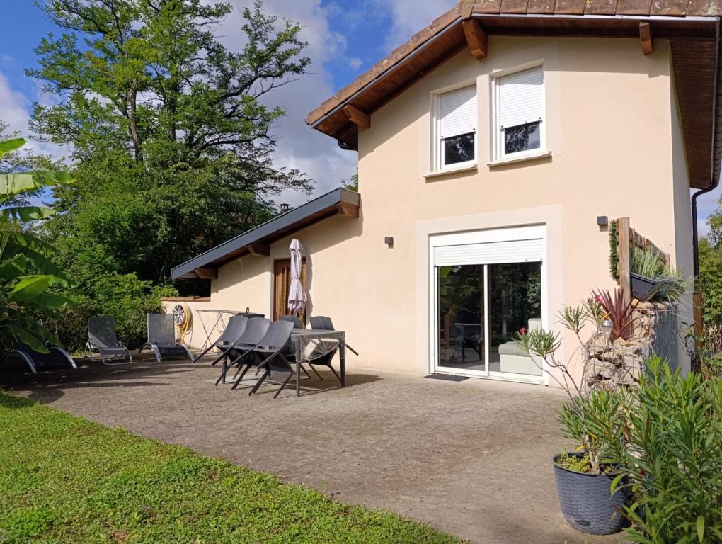 a house with a patio with chairs and an umbrella at La Maison au bord de l'Ain in Charnoz