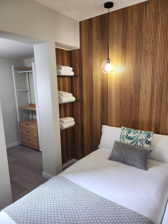 a bedroom with a white bed and a wooden wall at CREDENCIAL Bulevar in Sarria