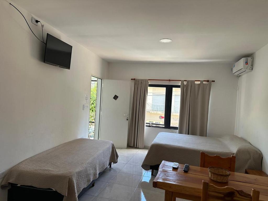 een kamer met twee bedden, een tafel en een tv bij departamentos apart quetzal in Villa Carlos Paz