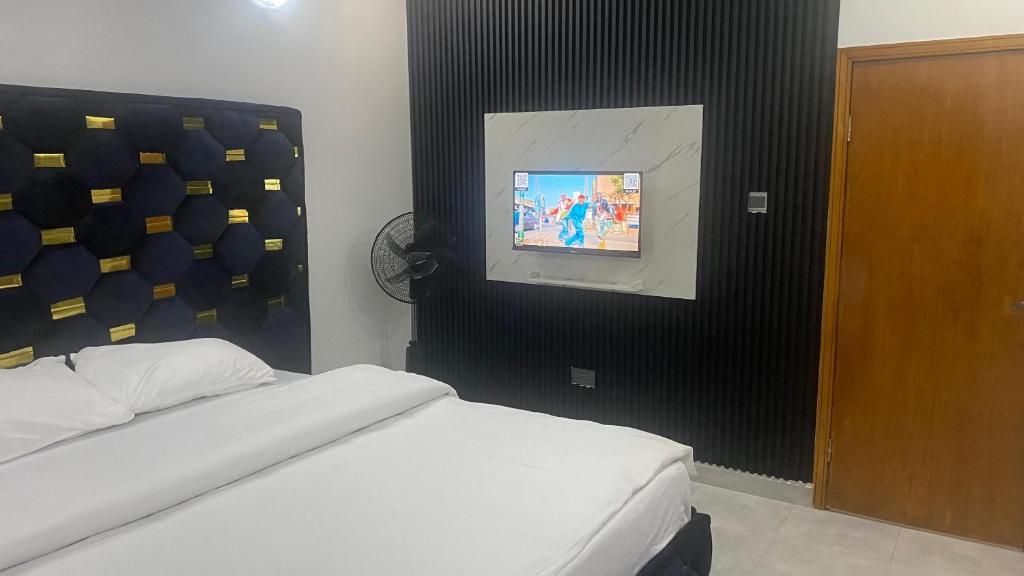 ein Schlafzimmer mit einem Bett und einem Fernseher an der Wand in der Unterkunft Apartments in Lekki in Lekki
