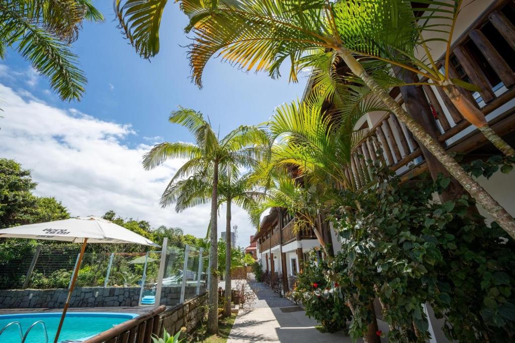 a resort with a swimming pool and palm trees at Pousada Buena Onda - 50m Da Praia - Ferrugem/SC in Garopaba