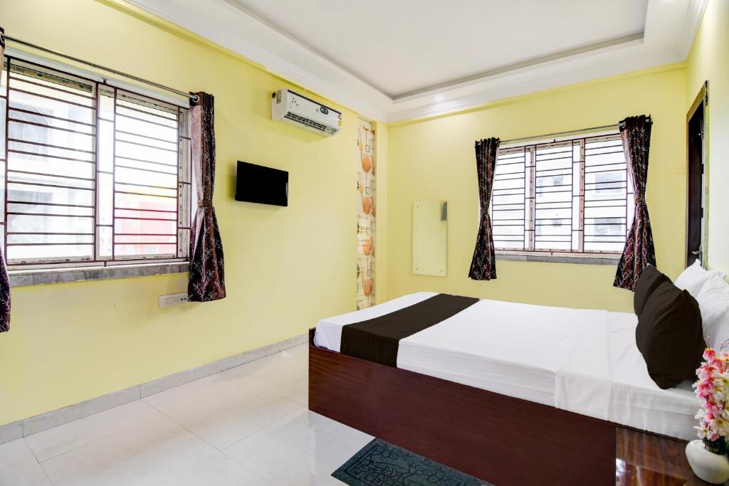 a bedroom with a bed and two windows at Hotel O TARA in Jojera