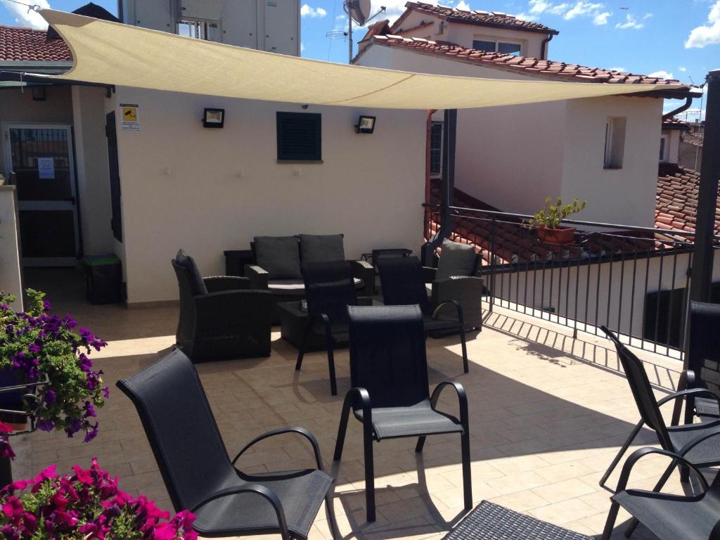 a patio with a bunch of chairs and an umbrella at Hotel Di Stefano in Pisa