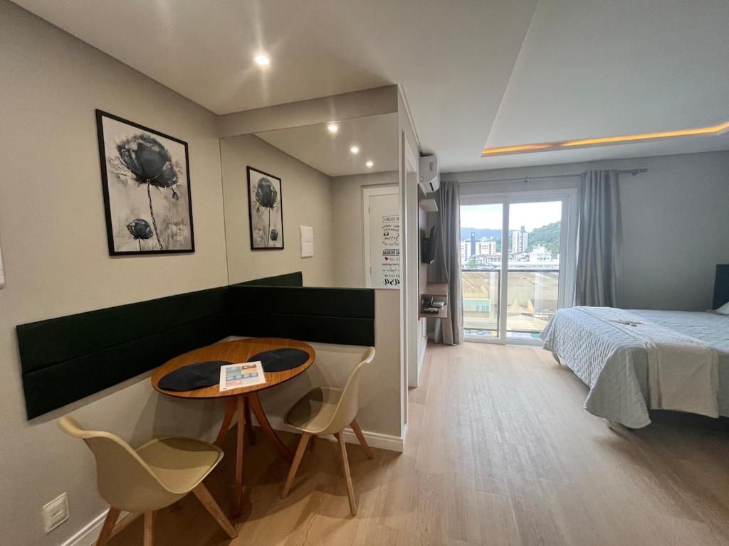 ein Schlafzimmer mit einem Bett und einem Tisch und Stühlen in der Unterkunft Loft Super aconchegante a 50mt da Vila Germânica com estacionamento gratuito in Blumenau