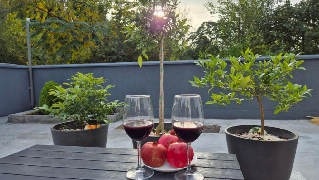 two glasses of wine and apples on a wooden table at WHITE HORTENZIA Guesthouse in Batumi