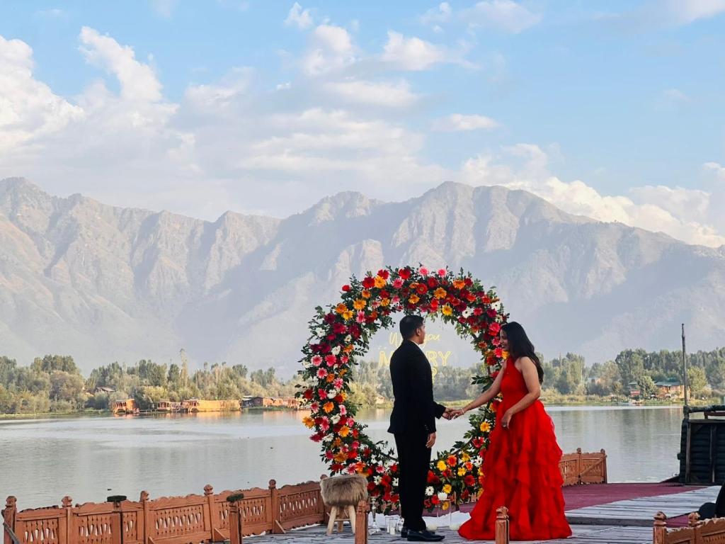 a bride and groom standing in front of a wreath at HB Freedom group of Houseboats in Srinagar