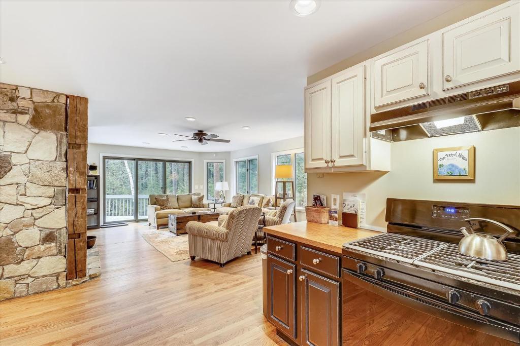 a kitchen with a stove and a living room at Spruce Pond Haven in Stowe