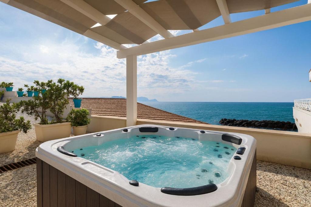 een hot tub op een patio met de oceaan op de achtergrond bij Amira Beach Villa by Le Dhome Sicily in Trappeto