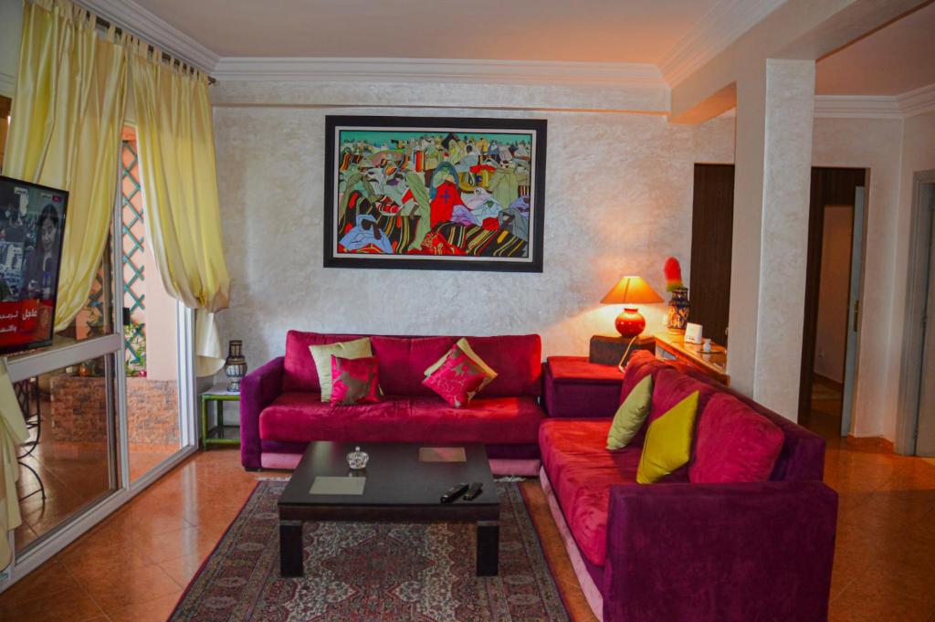 a living room with a red couch and yellow pillows at appartement el harti in Oulad Akkou