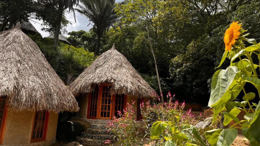 Una pequeña casa con dos techos de paja y flores. en TAWACA Junior, en Calabazo