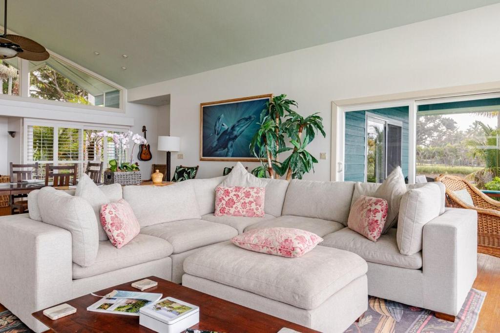 Grand Oceanfront Gated Estate on the Hamakua Coast في Hakalau: غرفة معيشة مع أريكة بيضاء مع وسائد وردية