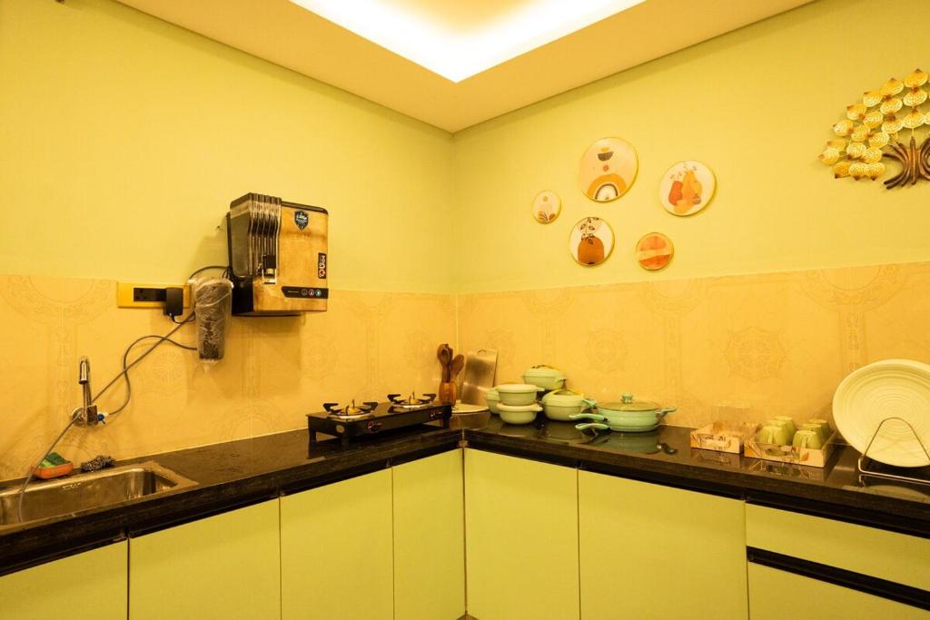 a kitchen with a counter with dishes on the wall at Green Home Stay - 10 Mins Walk to Kanyakumari Main Beach in Kanyakumari