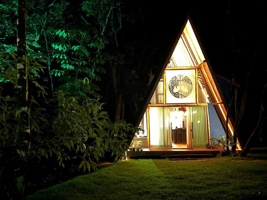 a house with a clock on the front of it at night at Tree of Life Chalet in Brumadinho
