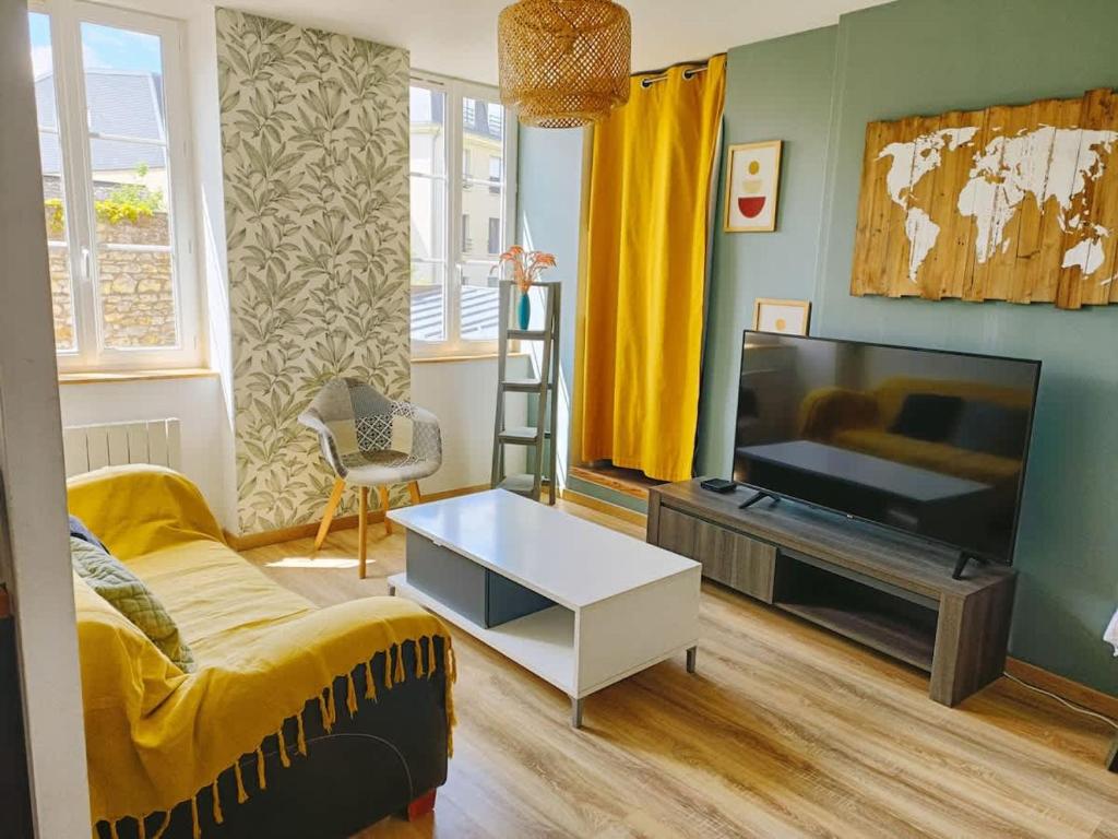 a living room with a couch and a flat screen tv at Le Duplex des Arcades - T2 lumineux hypercentre in Carentan
