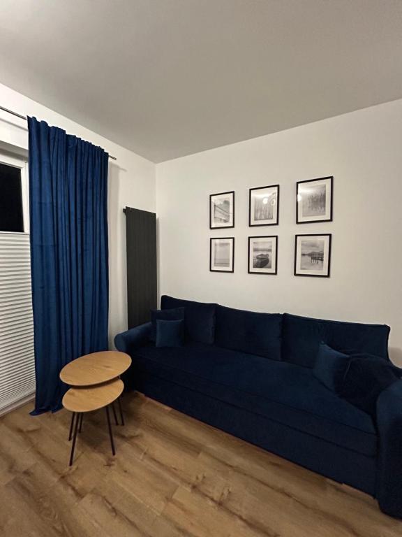 Una sala de estar con un sofá azul y una mesa. en Apartament Parkowa-prywatny parking, en Olecko