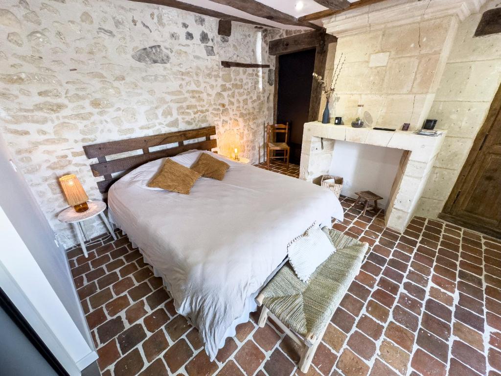a bedroom with a large bed and a fireplace at Le Logis de cœur in Azay-le-Rideau