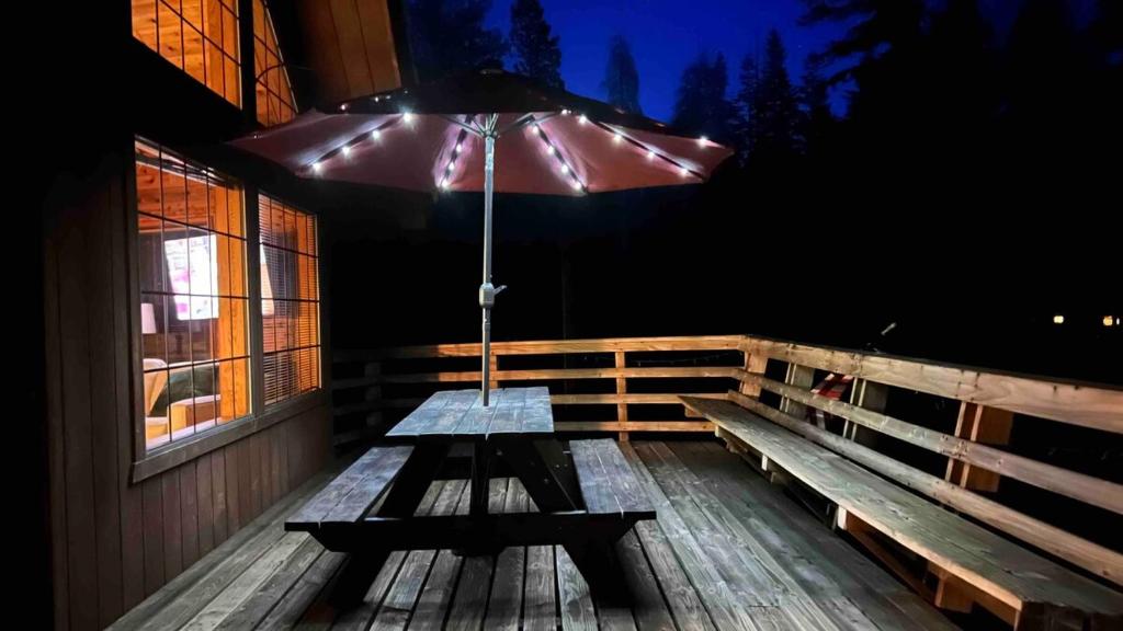 a picnic table with an umbrella on a deck at Little Bear Lodge in Springville