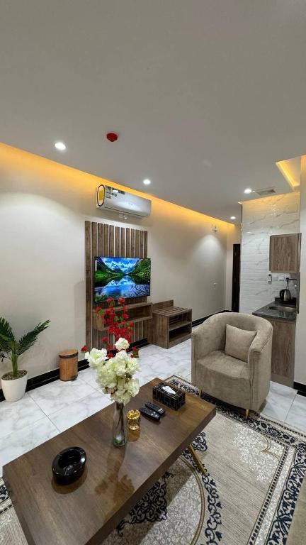 a living room with a table and a couch and a television at شقق يودج in Tabuk
