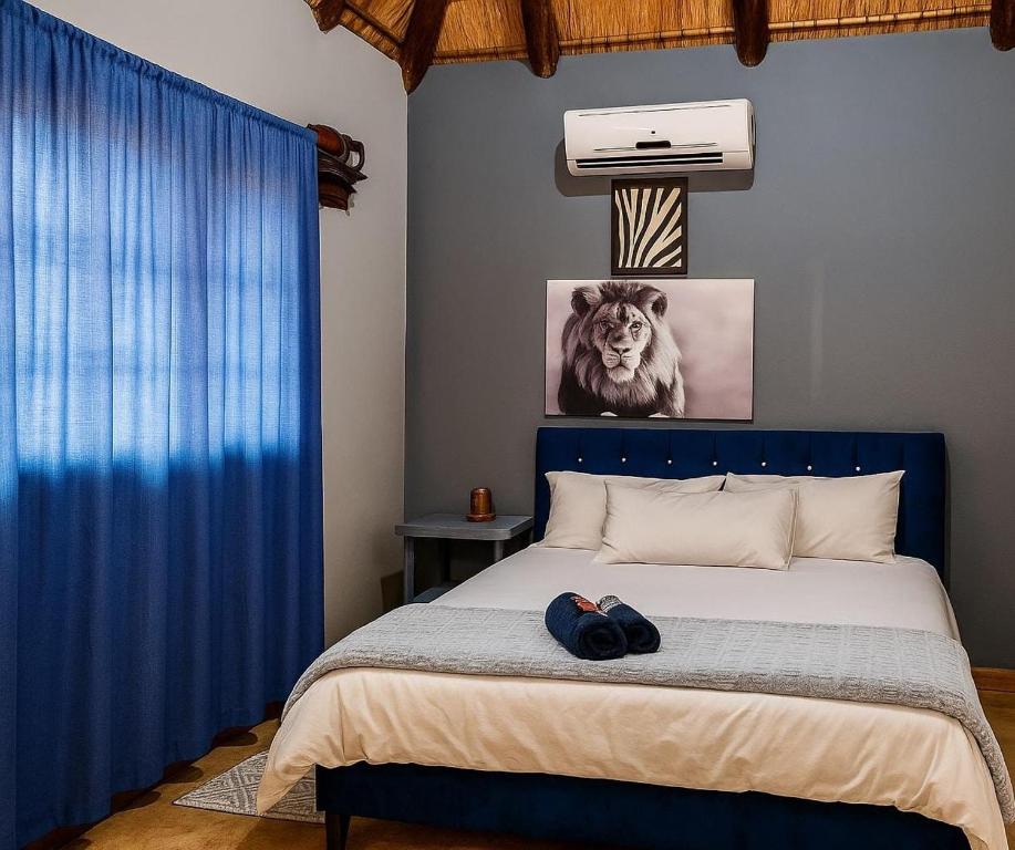 a bedroom with a blue bed with a lion picture on the wall at Clarky's Pride Lodge in Alldays