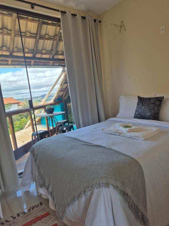 a bedroom with a bed and a large window at Pousada Contos da Lua Vaga in Milho Verde