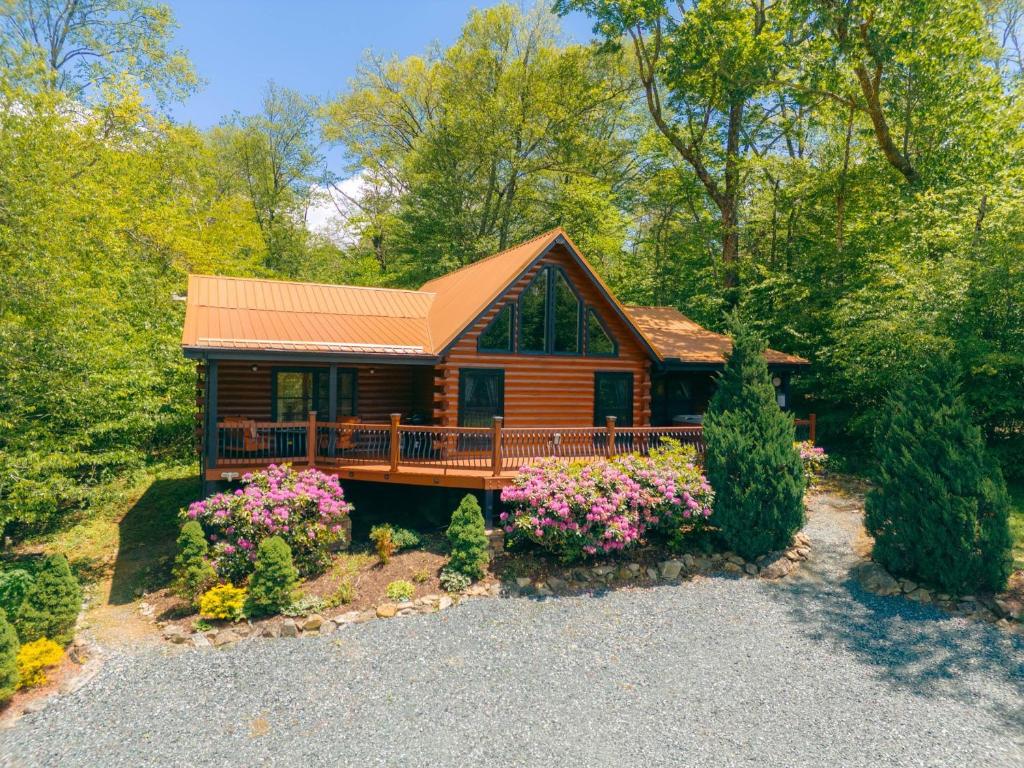 a cabin in the woods with flowers in front of it at Little Heaven in Banner Elk