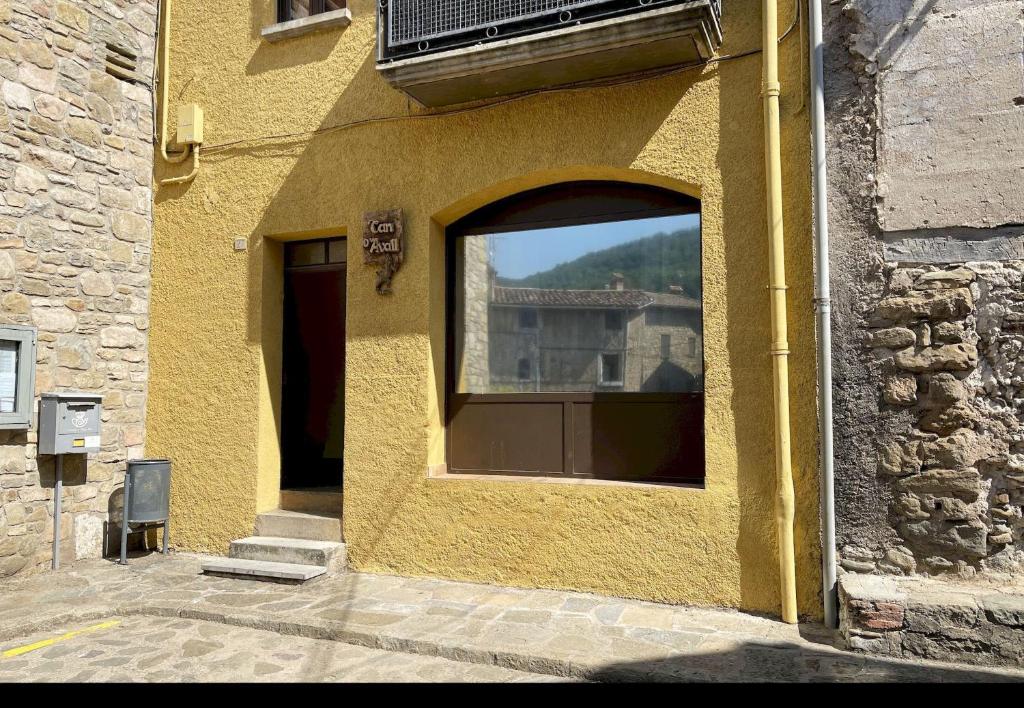 un bâtiment jaune avec une fenêtre sur le côté dans l'établissement Can d'Avall, à Riudaura