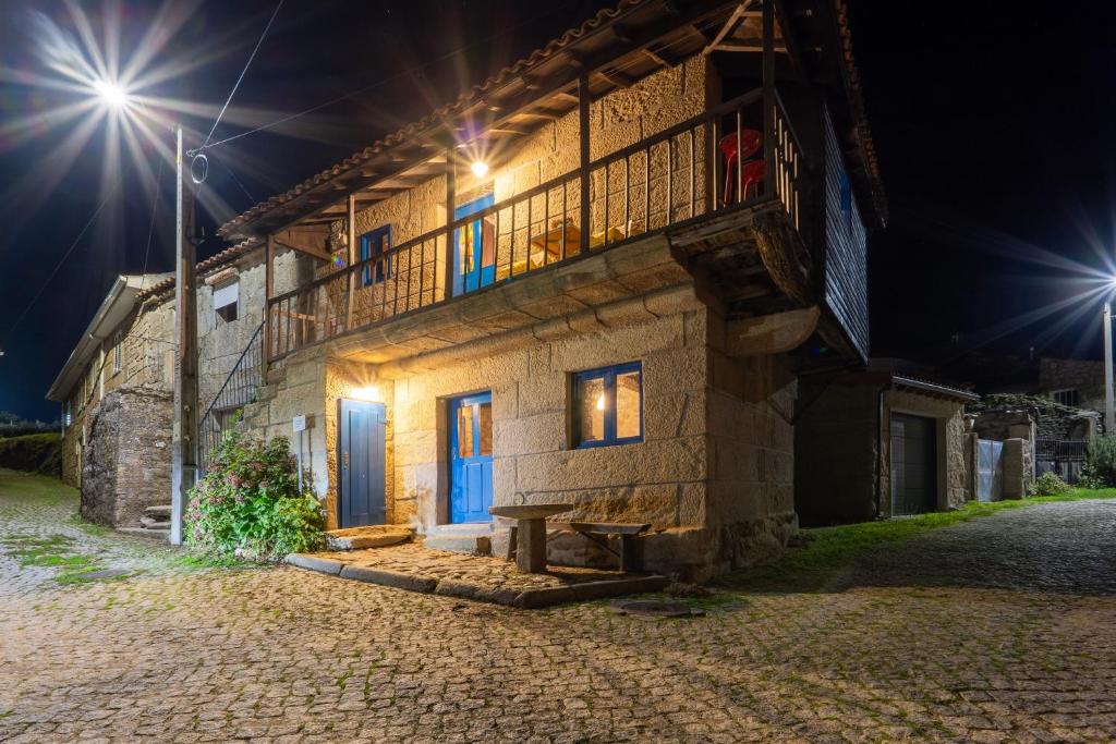 a stone house with a balcony at night at Casa do Sarracas in Vilar de Perdizes