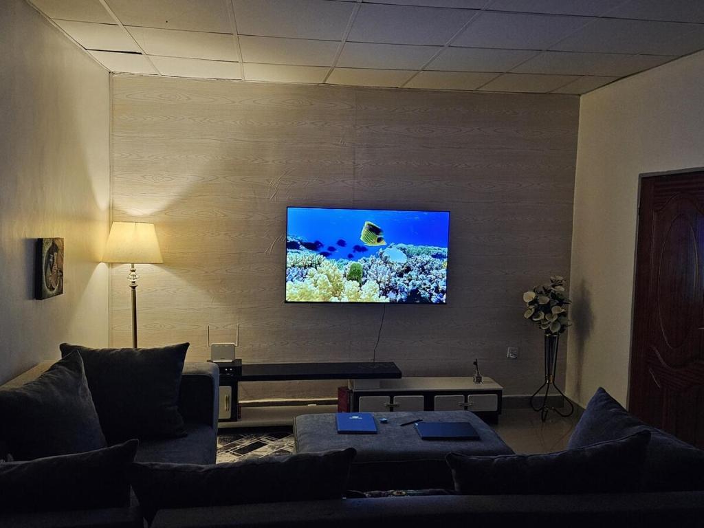 uma sala de estar com um sofá e uma TV na parede em Little Paradise em Kigali
