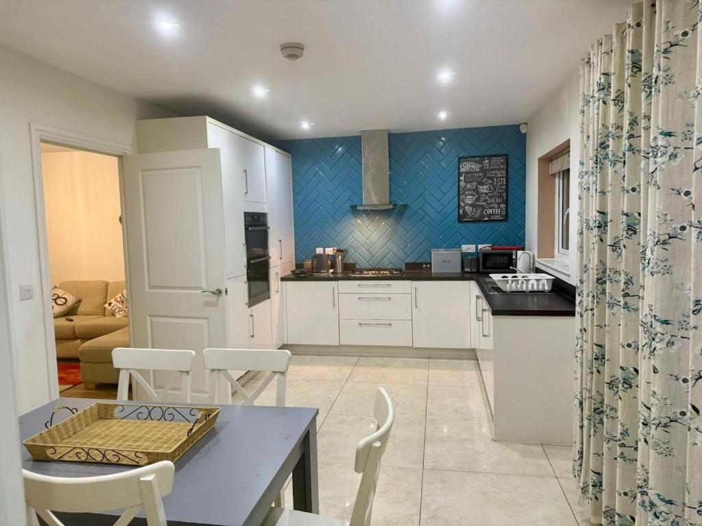 een keuken met witte kasten en een tafel en stoelen bij Woodley Haven House in Woodley