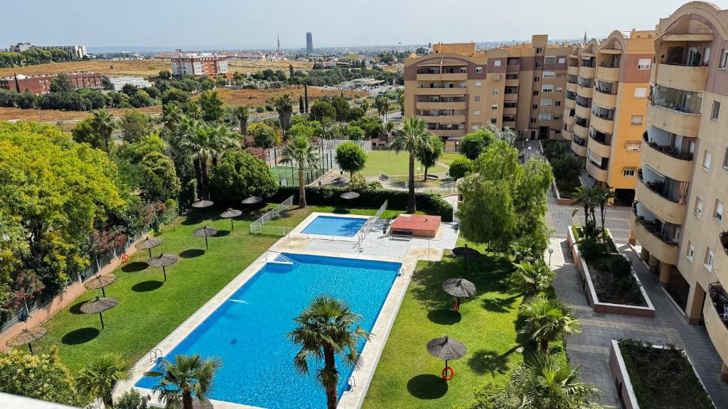 サン・ファン・デ・アスナルファラチェにあるVonitas vistas a Sevillaのプールとヤシの木と建物のあるアパート