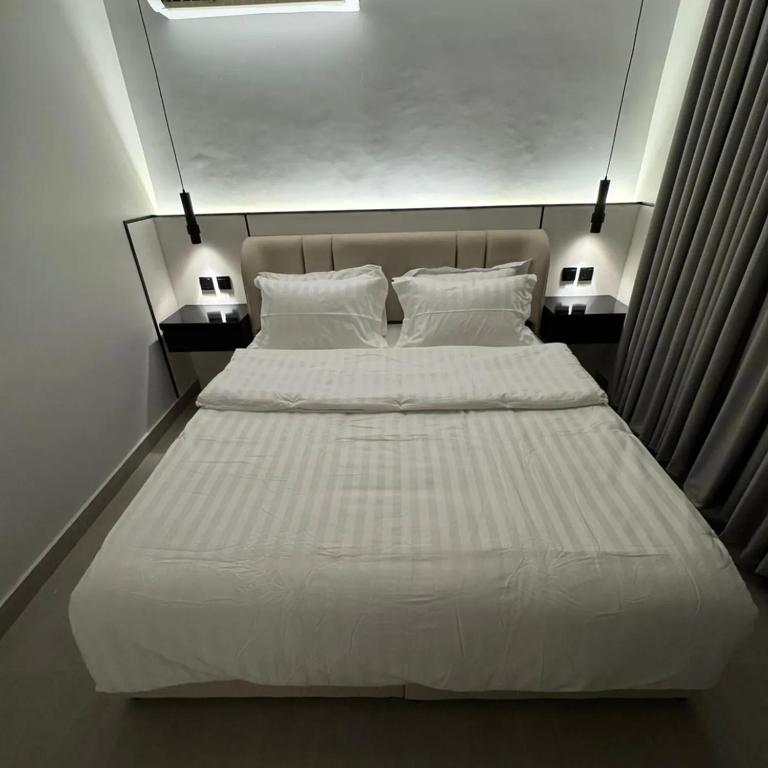 een bed met witte lakens en kussens in een kamer bij Smouha in Amman