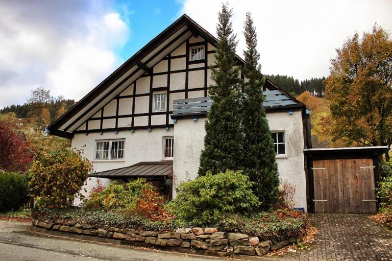 a large white house with a wooden garage at Landhaus am Bach in Winterberg