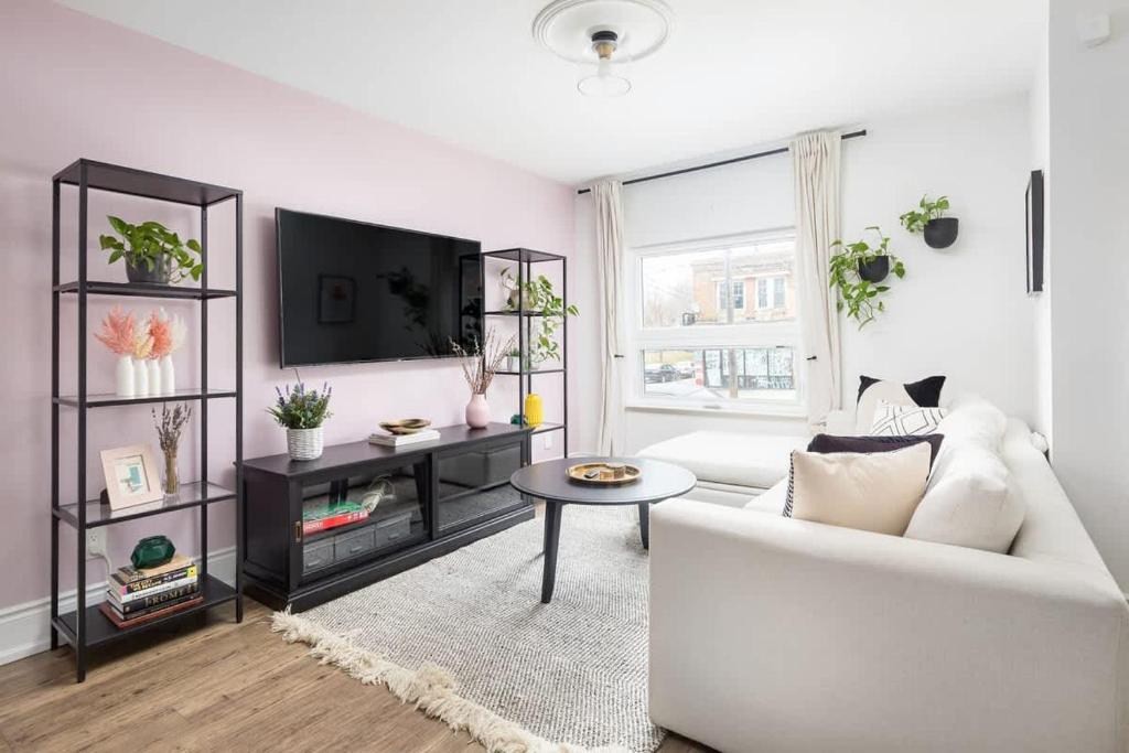 een woonkamer met een witte bank en een tv bij Charming 3 Beds Ossington Home in Toronto