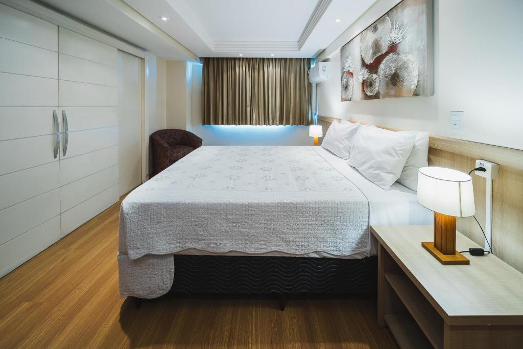 a hotel room with a bed and a desk and a window at Hotel Golden Park Curitiba By Nacional Inn in Curitiba