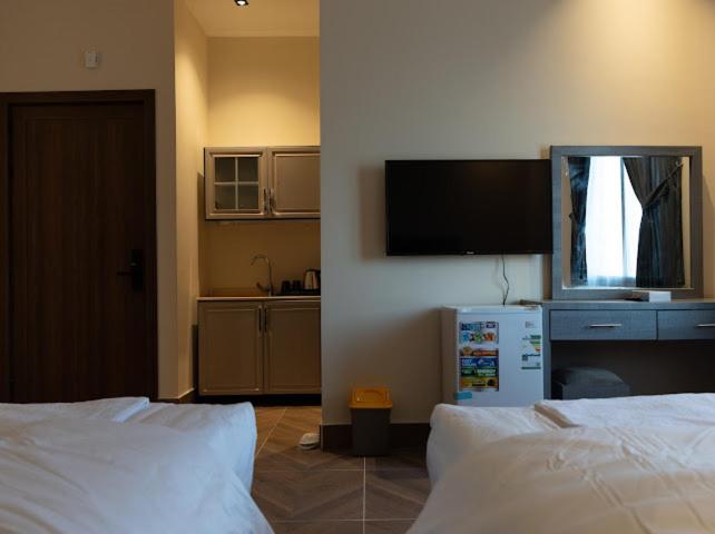 Un dormitorio con dos camas y un televisor de pantalla plana. en رايز العارض للشقق المخدومة, en Riad