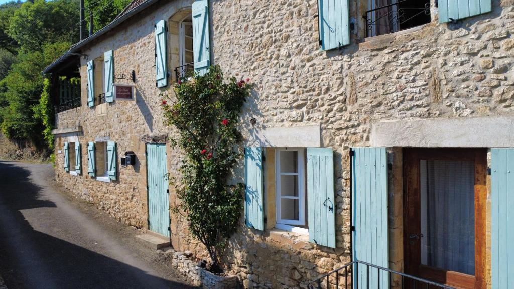 a stone building with blue doors and flowers on it at Le Coin Tranquille in La Roque-Gageac