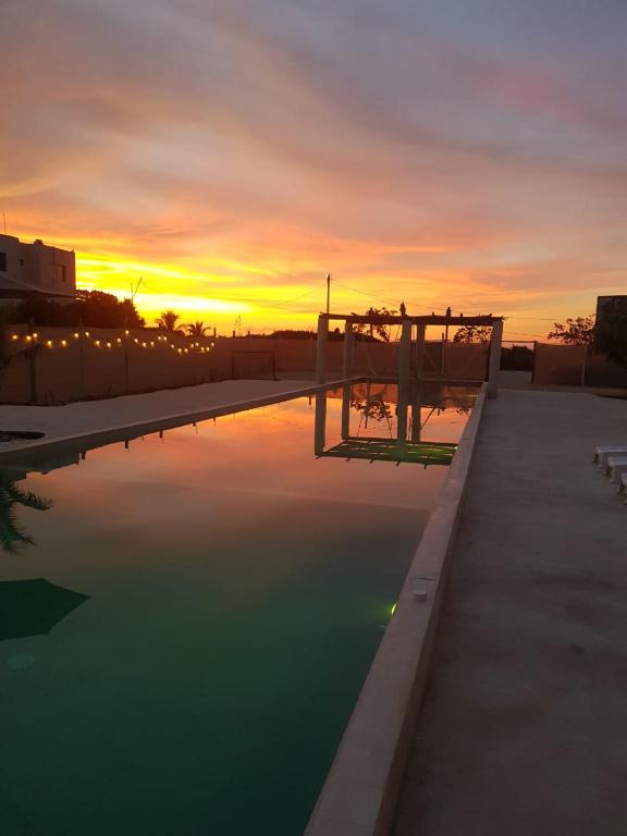 a pool of water with a sunset in the background at Villas Coral in Dzidzantún