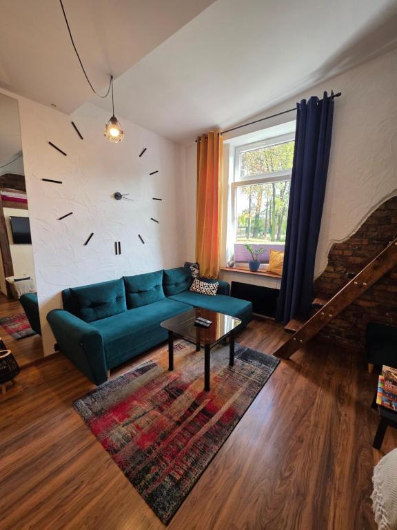 sala de estar con sofá verde y reloj en la pared en Loft, en Sosnowiec