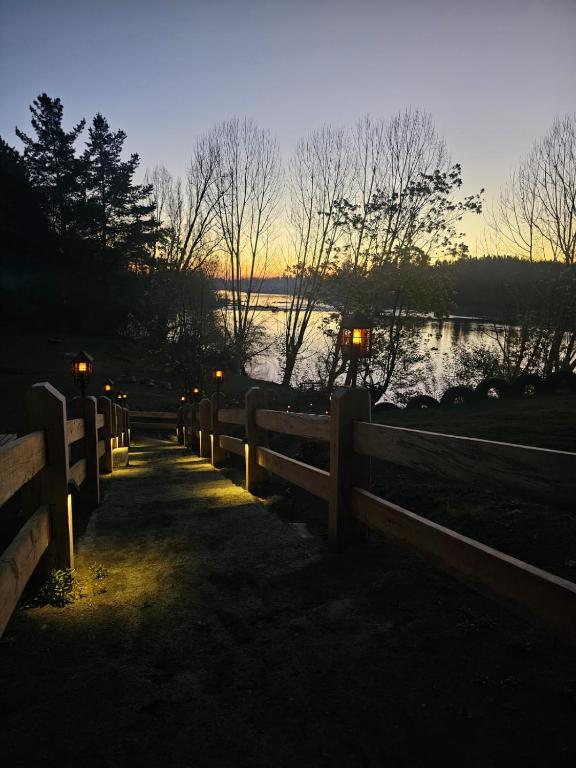 a fence next to a river with a sunset in the background at Camping Campeon in Salto del Laja