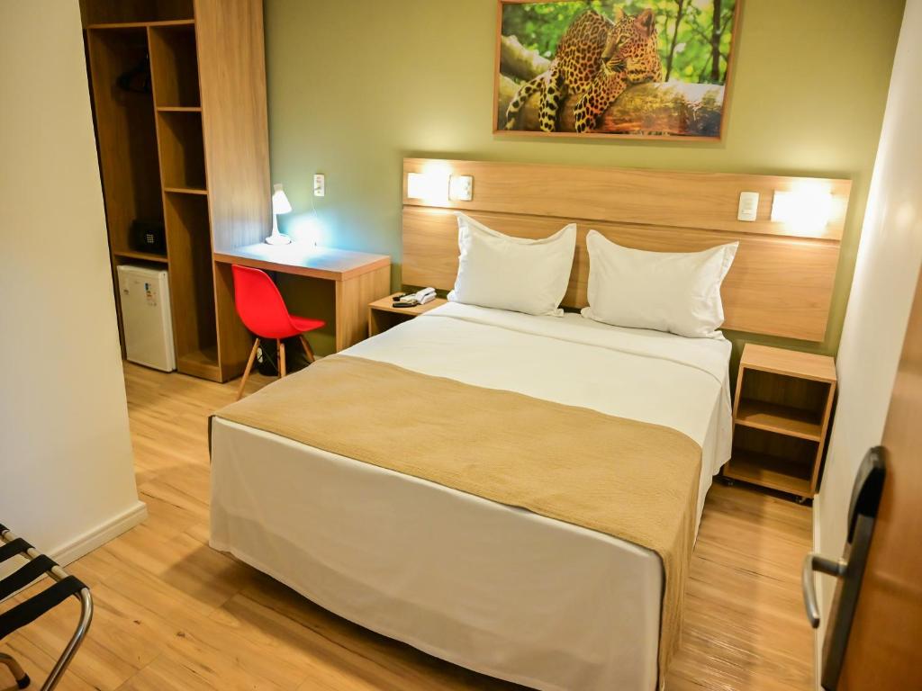 um quarto de hotel com uma cama e uma cadeira vermelha em Bristol Marambaia Belém em Belém