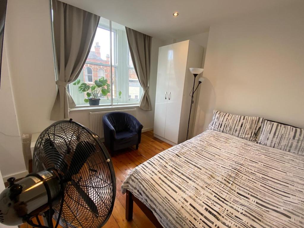 een slaapkamer met een ventilator, een bed en een raam bij Heart of Notts, Modern Studio, Great City Views in Nottingham