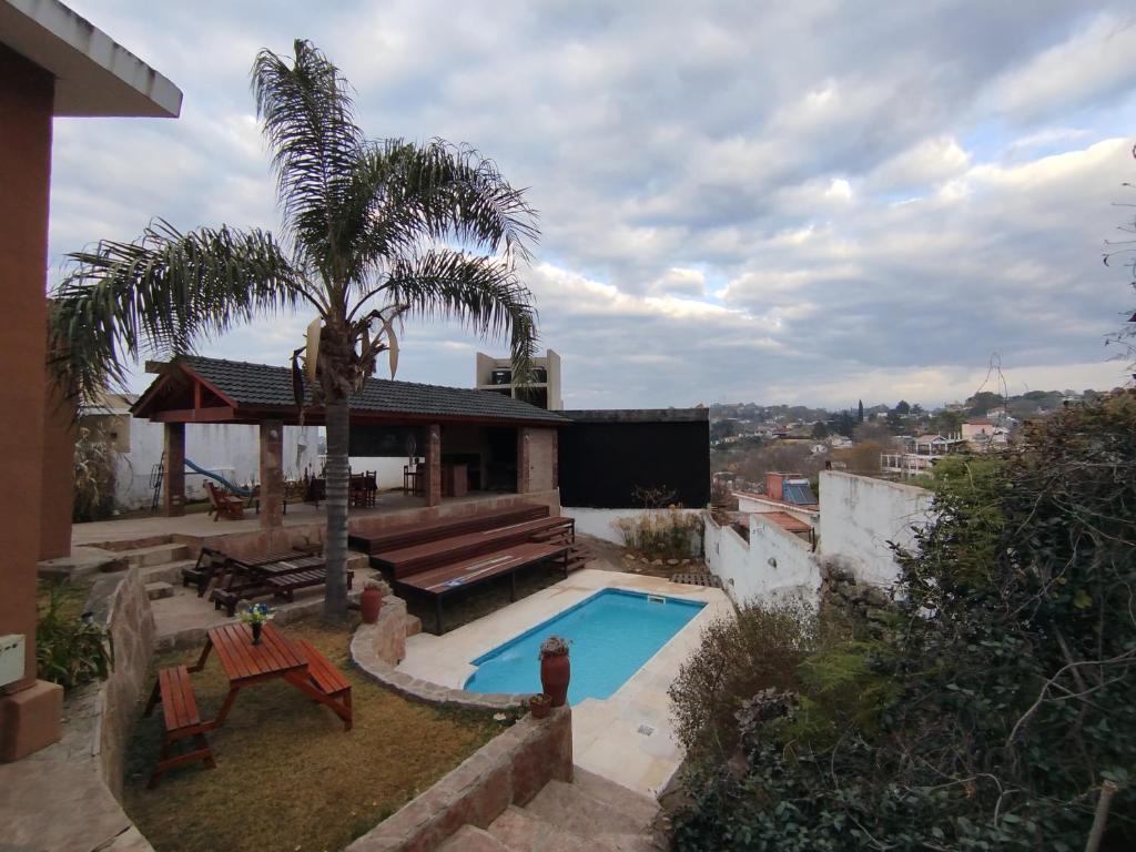 una casa con piscina y una palmera en Chalet " La Maruca ", en Villa Carlos Paz